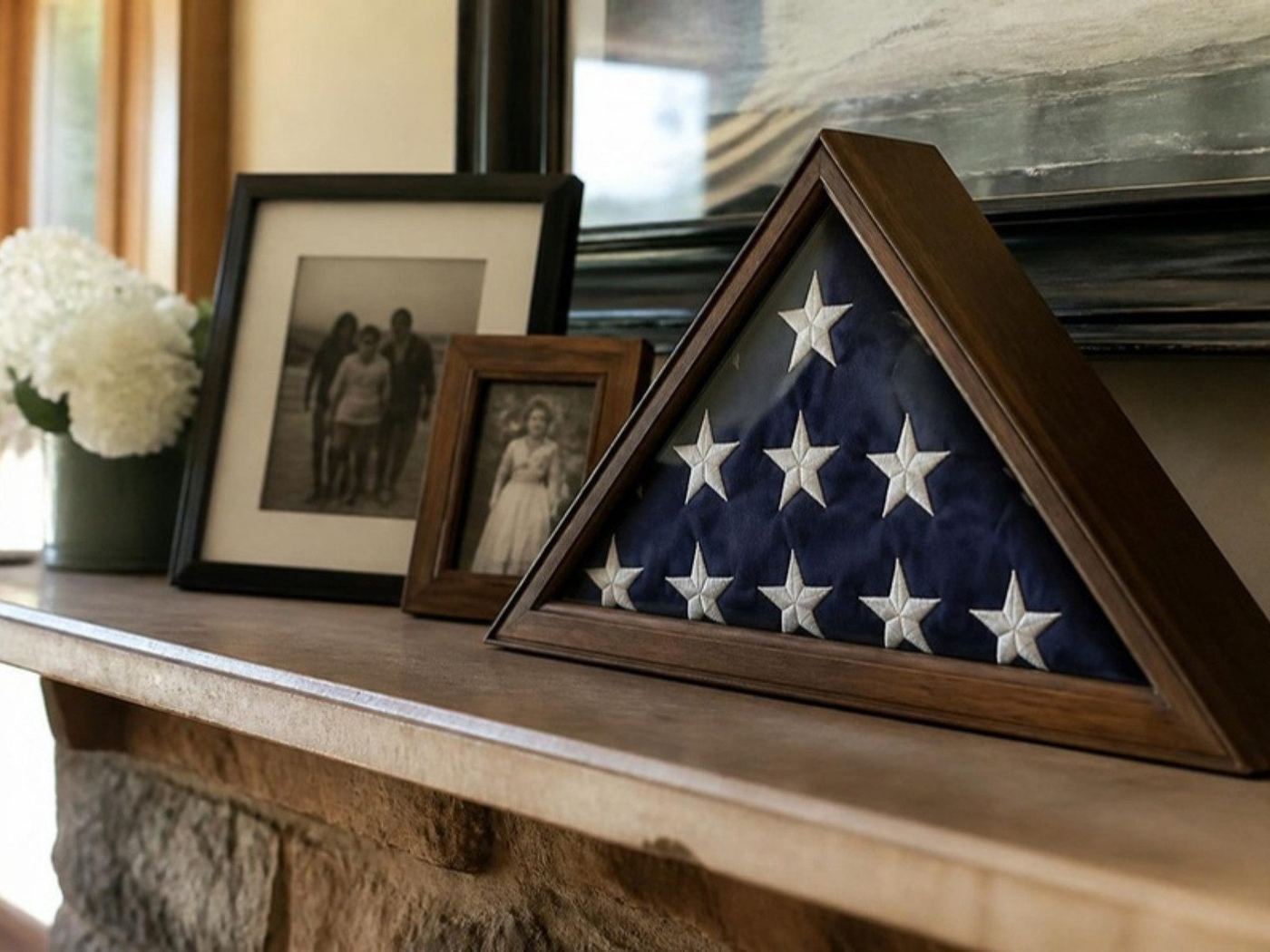 Folded American flag in a display case on a mantel beside family photos